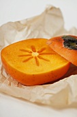 Persimmon with a slice removed on paper