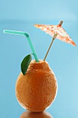 Tangerine with a straw and a cocktail umbrella