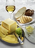 Sliced cheese, white wine, butter, grapes and bread