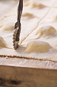 Herb ravioli being cut with a pastry cutter