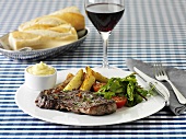 Beef steak with chips, salad and mayonnaise and a glass of red wine