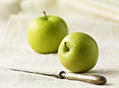 Zwei grüne Äpfel mit Messer