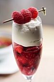 Strawberry dessert with cream garnished with skewered raspberries