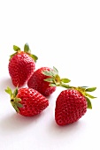 Five strawberries on a white surface