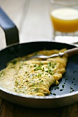Cheese omelette with chives in the frying pan