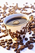 Eine goldene Tasse Kaffee von Kaffeebohnen umgeben