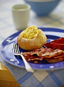 Scrambled egg in bread roll with bacon and tomato