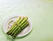 A bundle of green asparagus on white plate