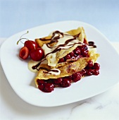 Crepes filled with cherries and covered in chocolate sauce