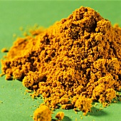 A heap of curry powder on green background