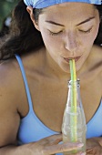 Young woman in bikini drinking lemonade