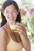 Junge Frau hält Glas mit Orangensaft