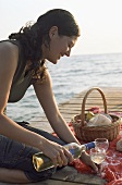 Young woman pouring white wine on a jetty