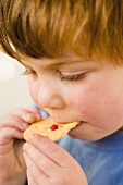 A boy biting into a biscuit