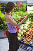Junge Frau beim Kauf von Karotten im Supermarkt