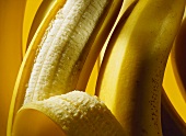 Bananen, eine halb geschält