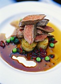 Lamb fillets on potatoes in beetroot sauce with peas