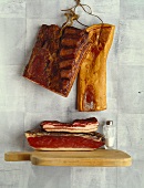 Various types of bacon, some hanging on the wall