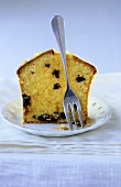 A piece of orange Madeira cake on plate with fork