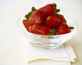 Strawberries with leaves in glass bowl