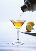 Cocktail aus Shaker in Glas gießen