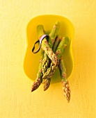 Green asparagus in bowl with elastic band