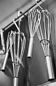 Several whisks hanging in a kitchen