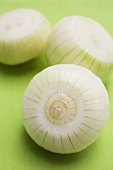 Three white onions, each with a slice cut off