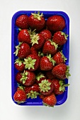 Fresh strawberries in blue plastic punnet (overhead view)