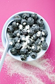 Sugared blueberries in white bowl with spoon
