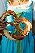 Girl in national dress holding giant pretzel (Oktoberfest, Munich)