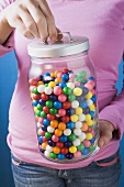 Woman holding jar of coloured bubblegum balls