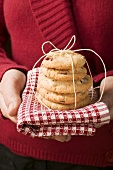 Hands holding cranberry biscuits on checked cloth