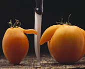 Two tomatoes with noses, knife between them