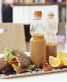 Vegetable soup in bottles, sandwich and orange for lunch
