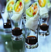 Rice paper rolls filled with vegetables in glasses of soy sauce