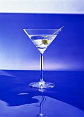 A glass of Martini with green olive