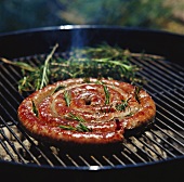 Coiled sausage with rosemary on the barbecue