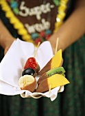 Chocolate-coated fruit on wooden cocktail sticks