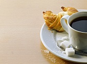 A cup of coffee with croissant