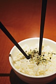 Eine Schale Reis mit Gewürzen und Essstäbchen