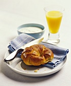 A croissant with a glass of orange juice and yoghurt