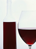A glass of red wine with a red wine bottle