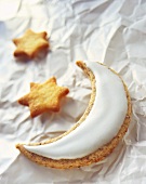 Moon biscuit with glacé icing and star biscuits on paper