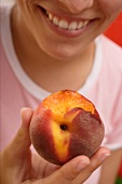Woman holding a peach with a bite taken