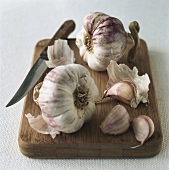 Garlic with knife on wooden board