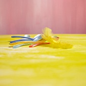 Coloured egg spoons and yellow feathers
