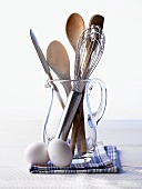 Kitchen utensils in a carafe, kitchen cloth and two eggs