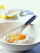 Teigherstellung: Eier und Mehl in einer Schüssel, Schneebesen