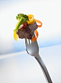 Small piece of beef on a fork with vegetables